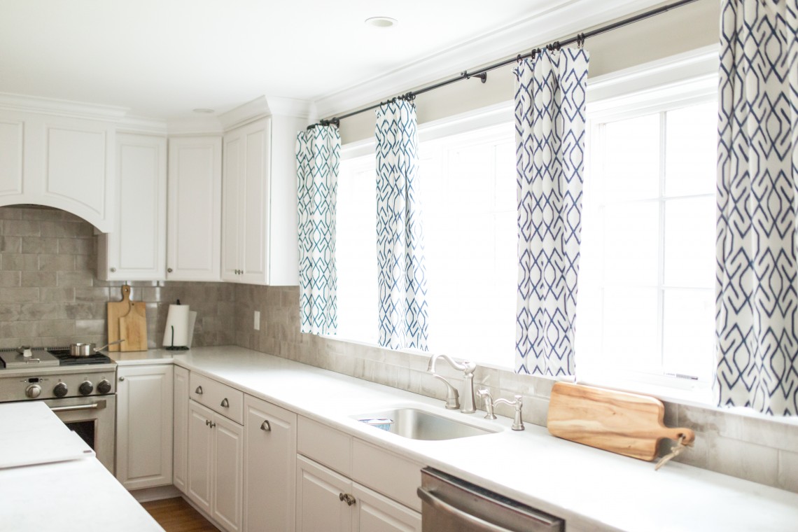 A kitchen with white cabinets and black and blue curtains