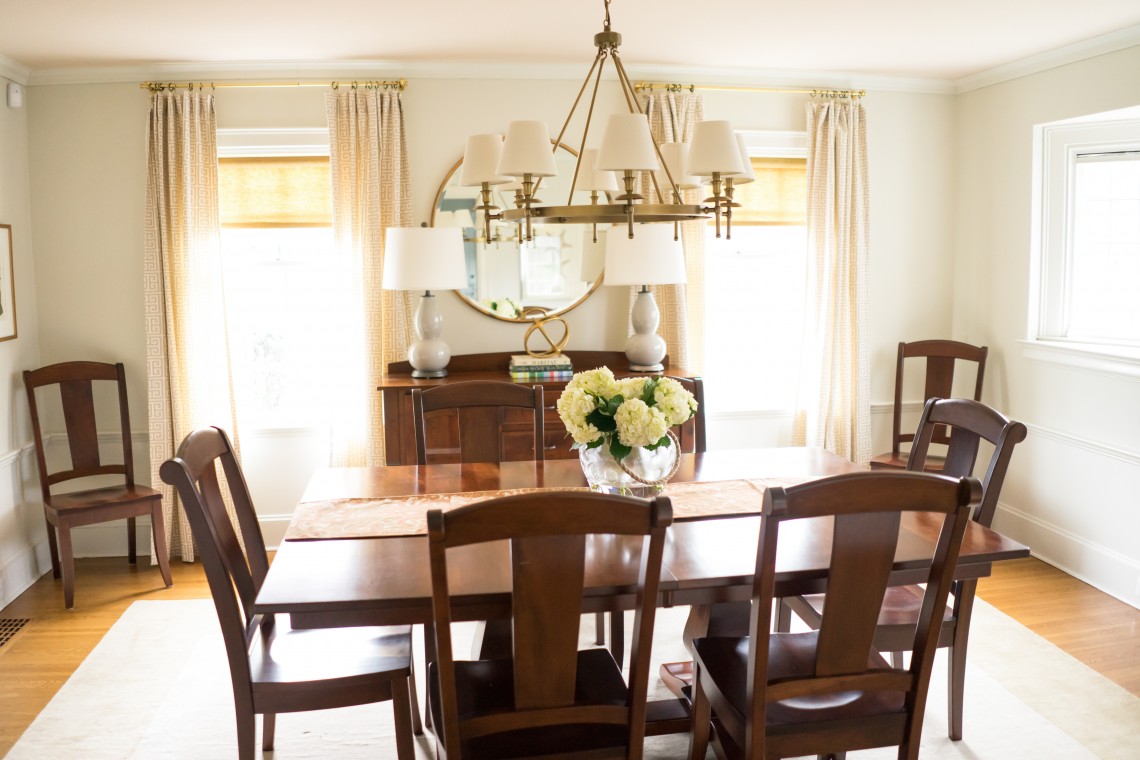 A dining room table with chairs and flowers in the center.