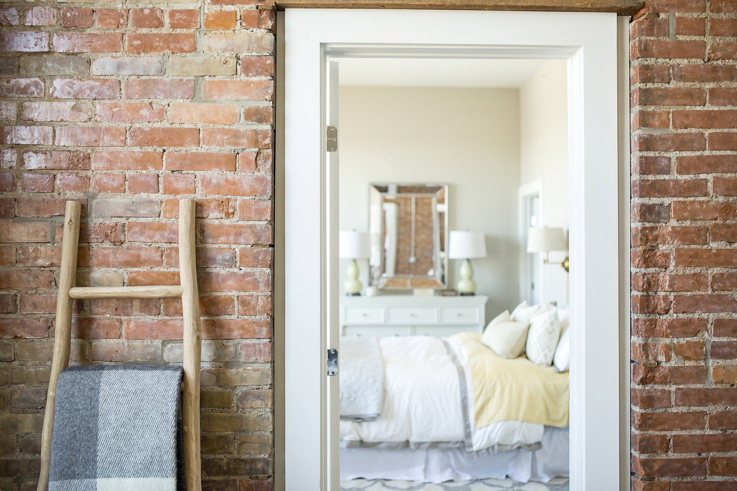 A bedroom with brick walls and white furniture.