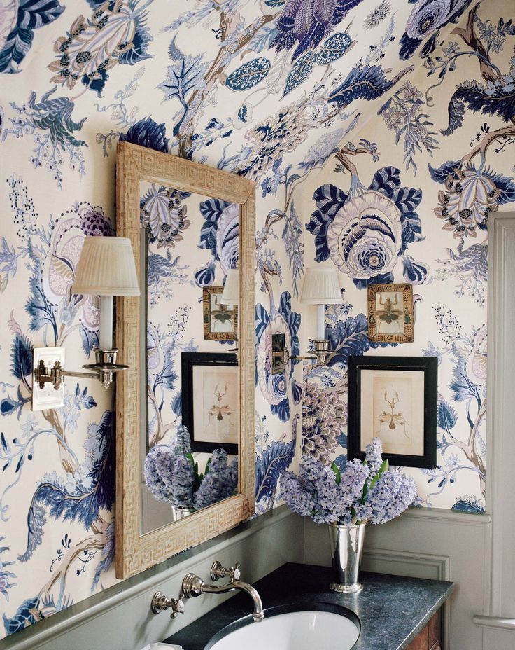 A mirror and wall in a bathroom with blue flowers.