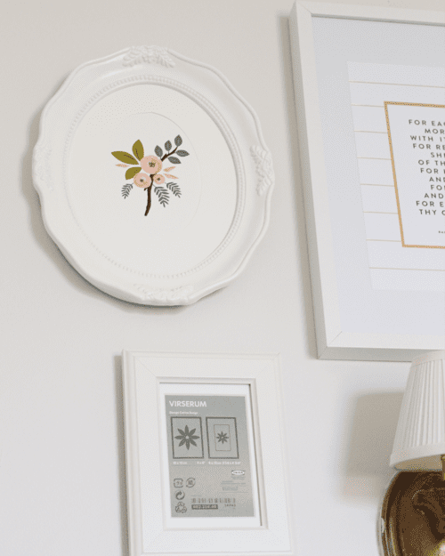 A white plate with a flower on it hanging from the wall.