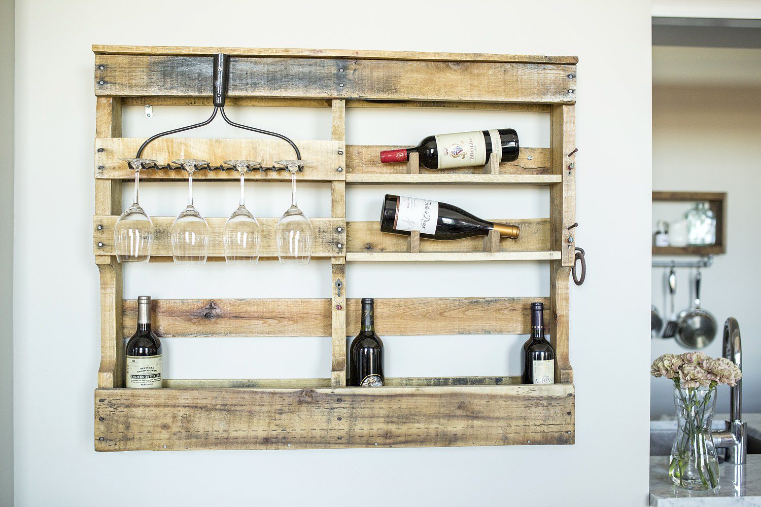 A wooden pallet with wine glasses and bottles on it.
