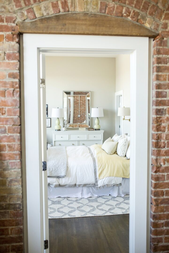 A bedroom with brick walls and white furniture.