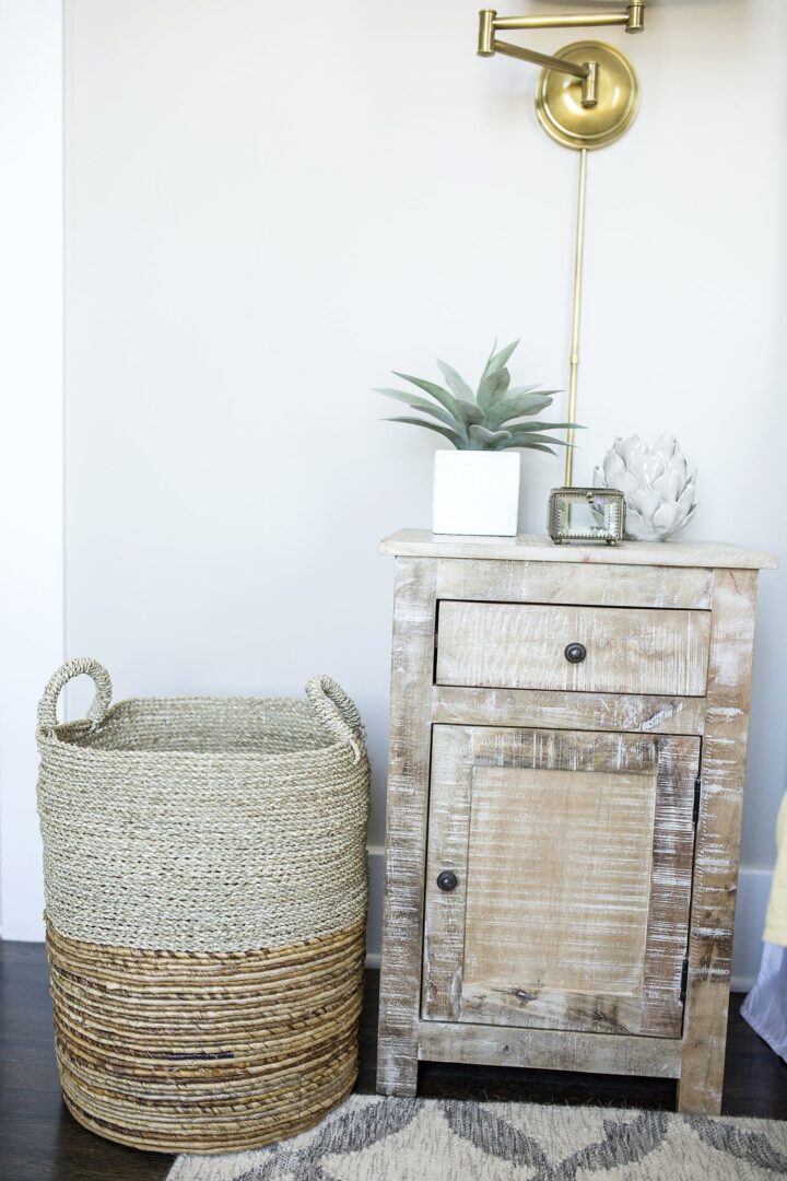 A white dresser and basket on the floor