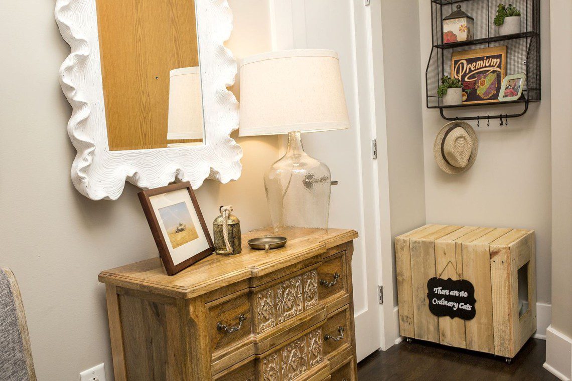 A table with a lamp and mirror in the corner of a room.