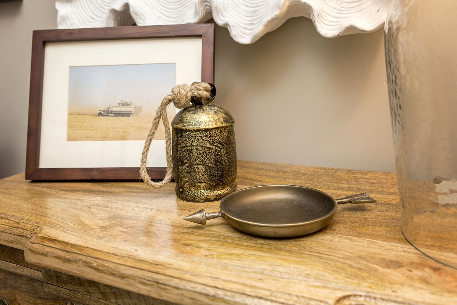 A picture of a table with a small frying pan and a brass bell.