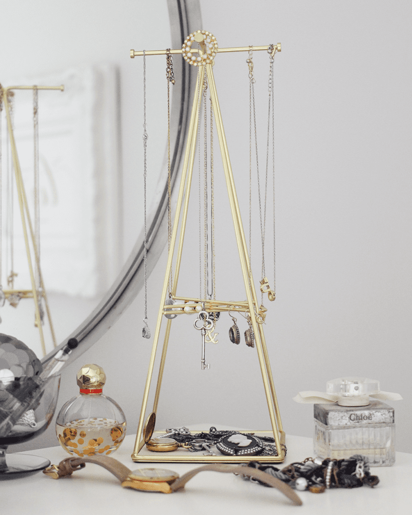 A gold jewelry stand with many different necklaces.