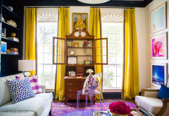 A living room with yellow curtains and purple rug.