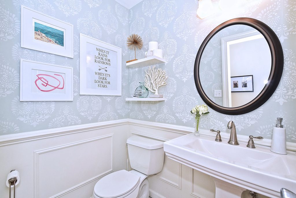 A bathroom with a toilet, sink and mirror.