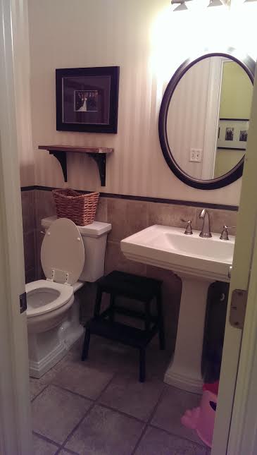 A bathroom with a toilet, sink and mirror.