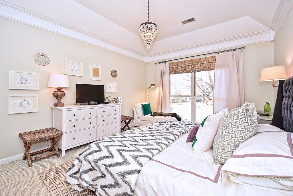 A bedroom with a bed, dresser and tv.