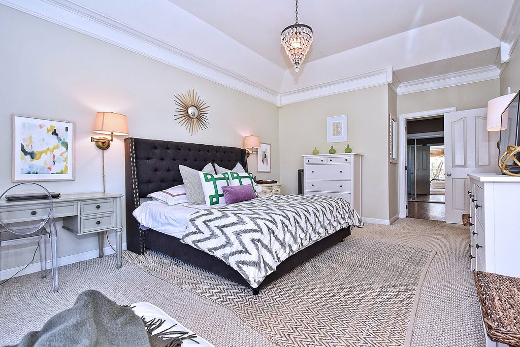 A bedroom with a bed, dresser and mirror.