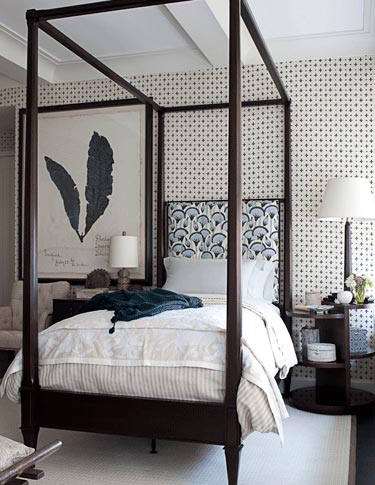 A bedroom with four poster bed and white walls.