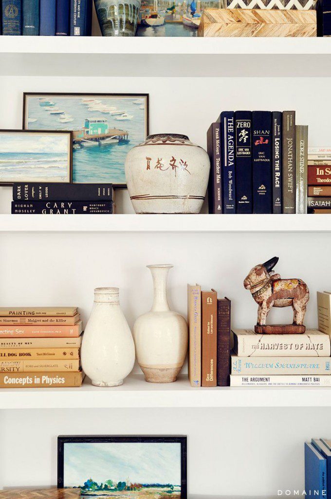 A shelf with books and vases on it