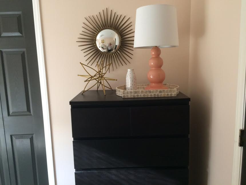 A dresser with a lamp and mirror on it