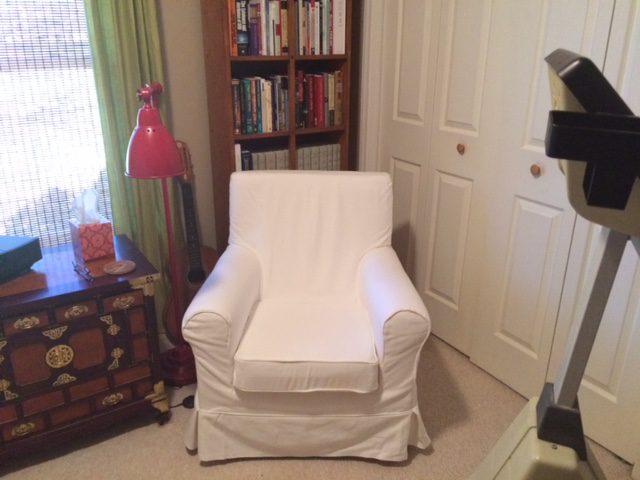 A white chair in front of a bookcase.