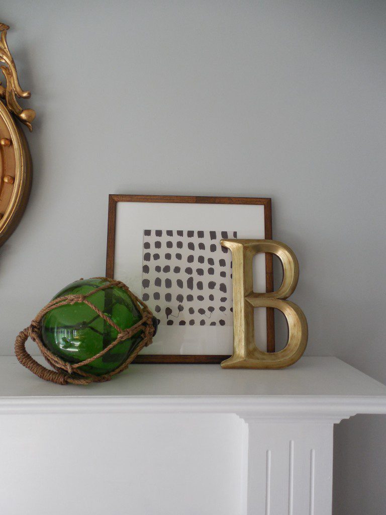 A green ball and some gold letters on top of a white mantle.