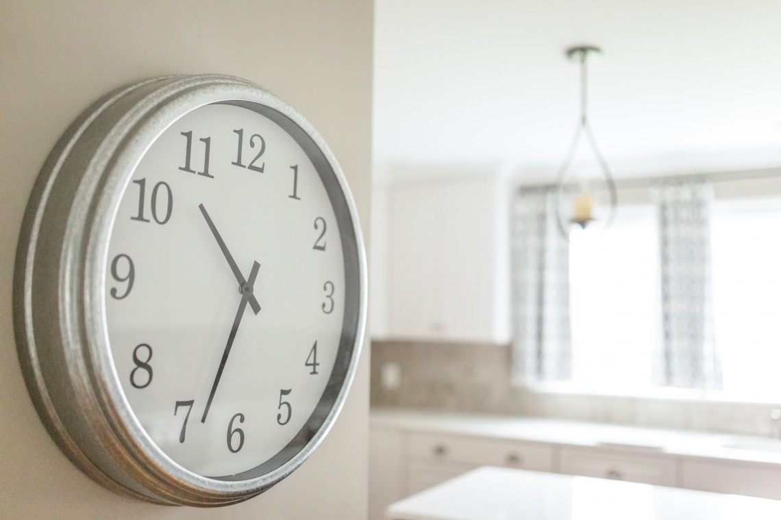A clock hanging on the wall in a kitchen.
