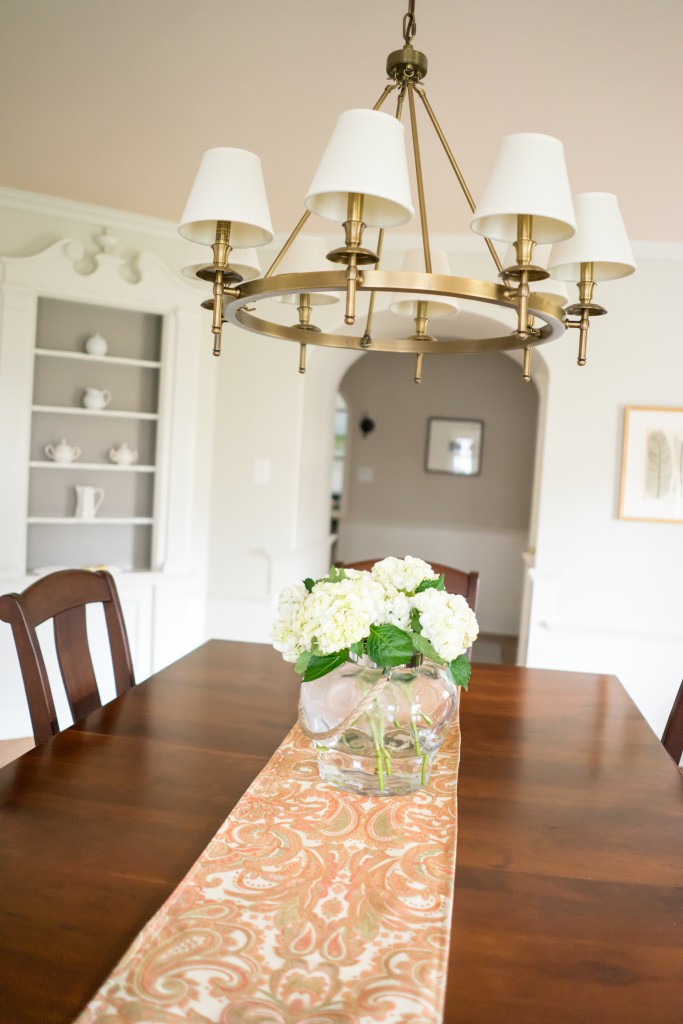 A dining room table with flowers in the center.