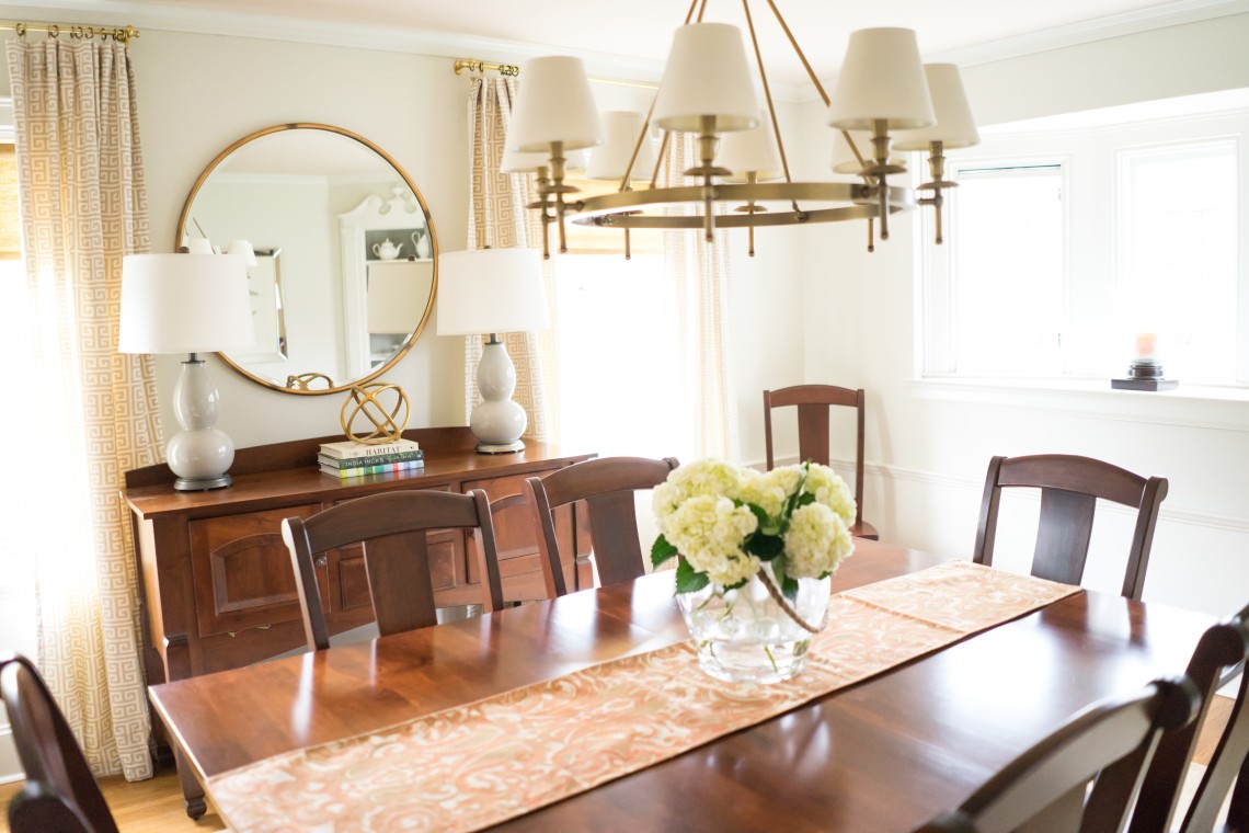 A dining room table with flowers in the center.