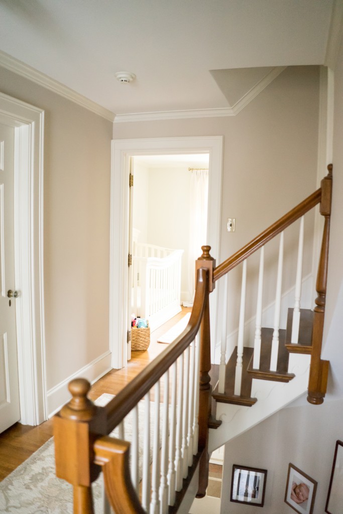 A hallway with stairs and a door way.