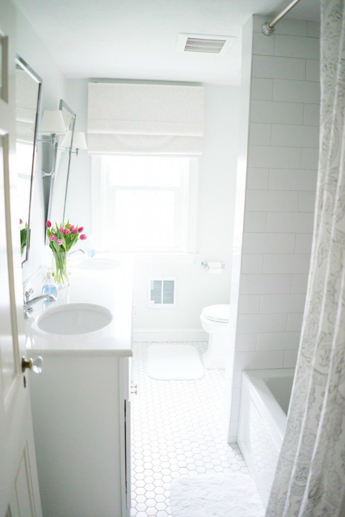 A bathroom with white tile floors and walls.