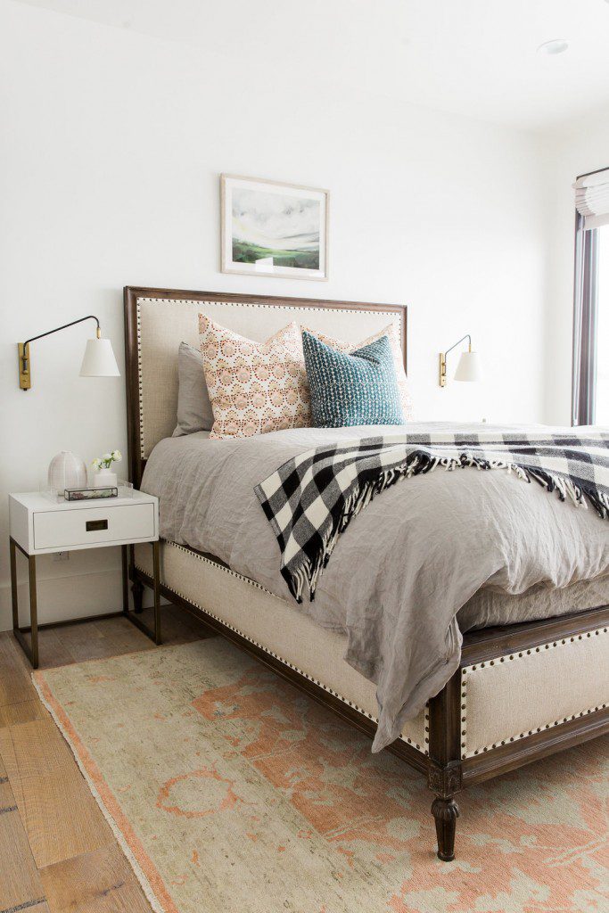 A bedroom with a bed, nightstand and lamps.