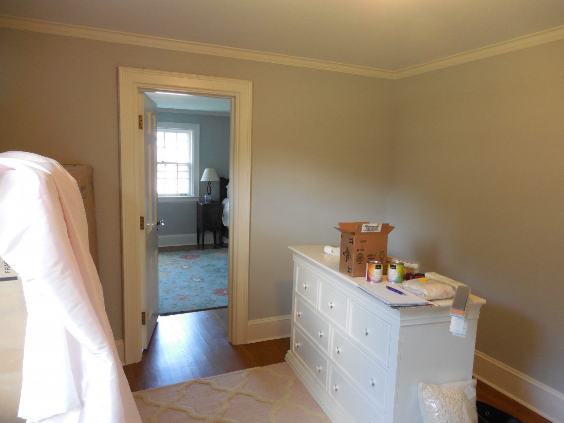 A bedroom with a dresser and a door open.