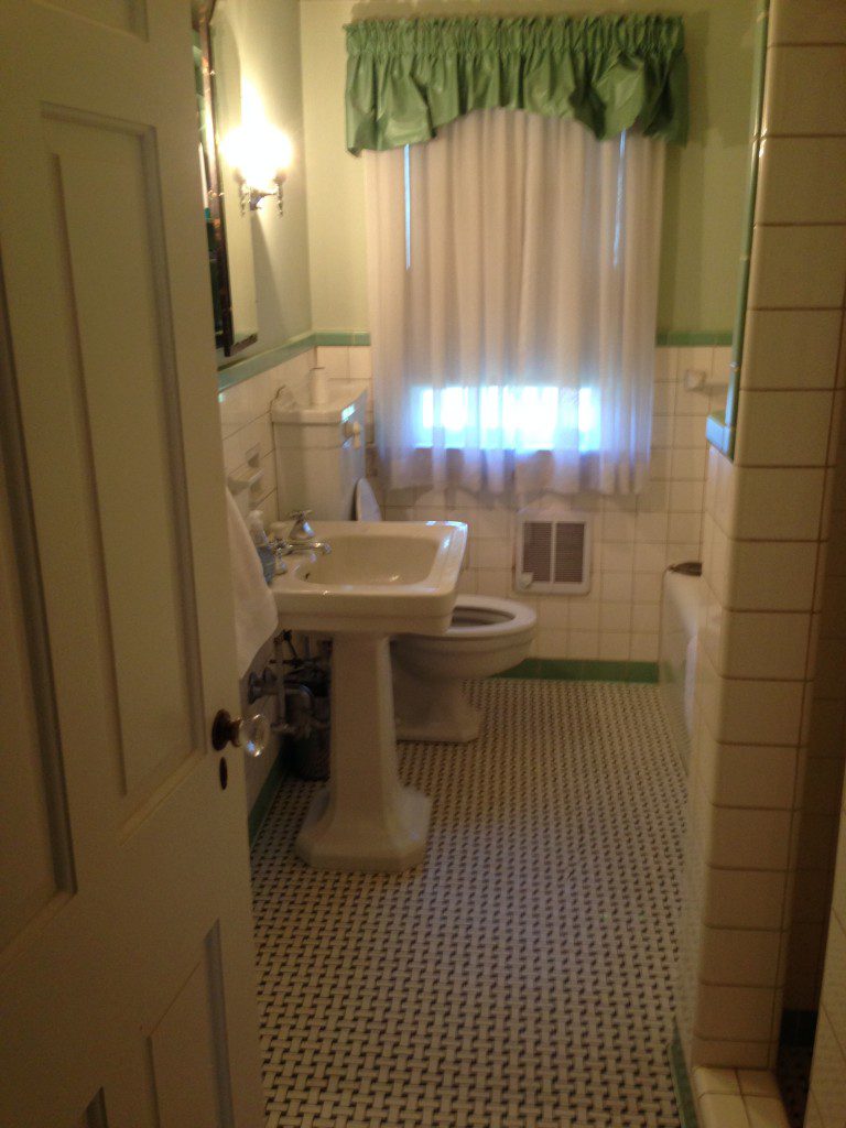 A bathroom with a toilet, sink and mirror.