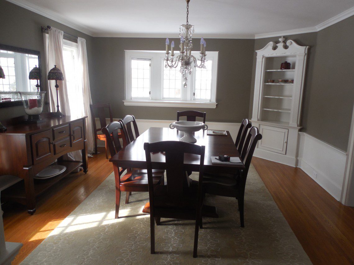 A dining room with a table and chairs, a chandelier and a cabinet.