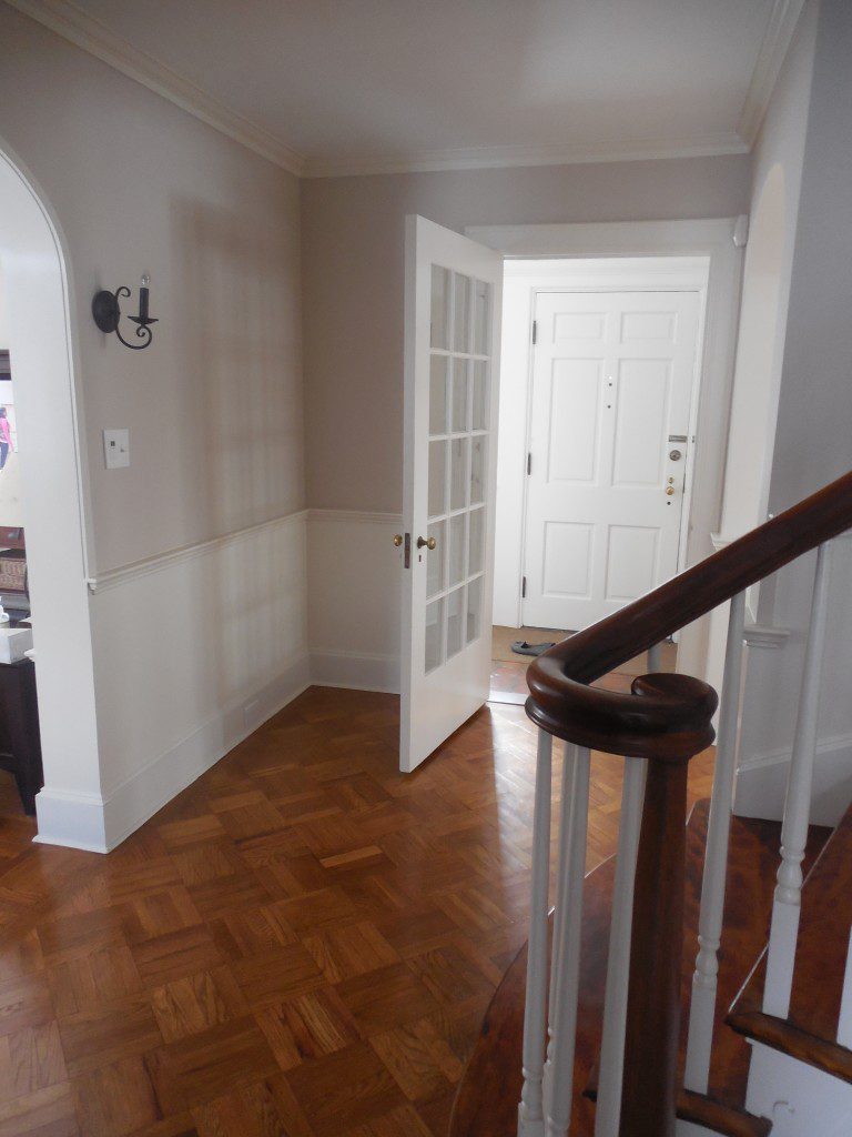 A white door and wooden floor in the hallway of a house.