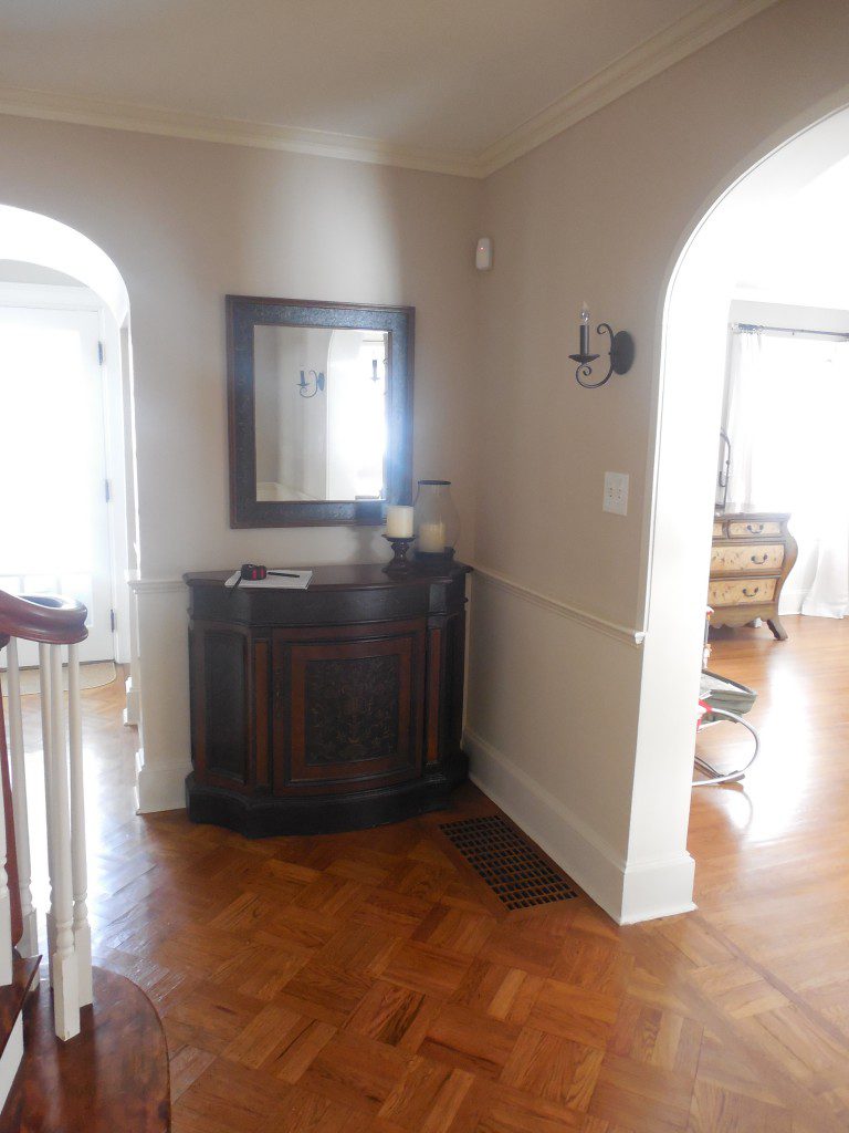 A hallway with a mirror and a wooden cabinet.