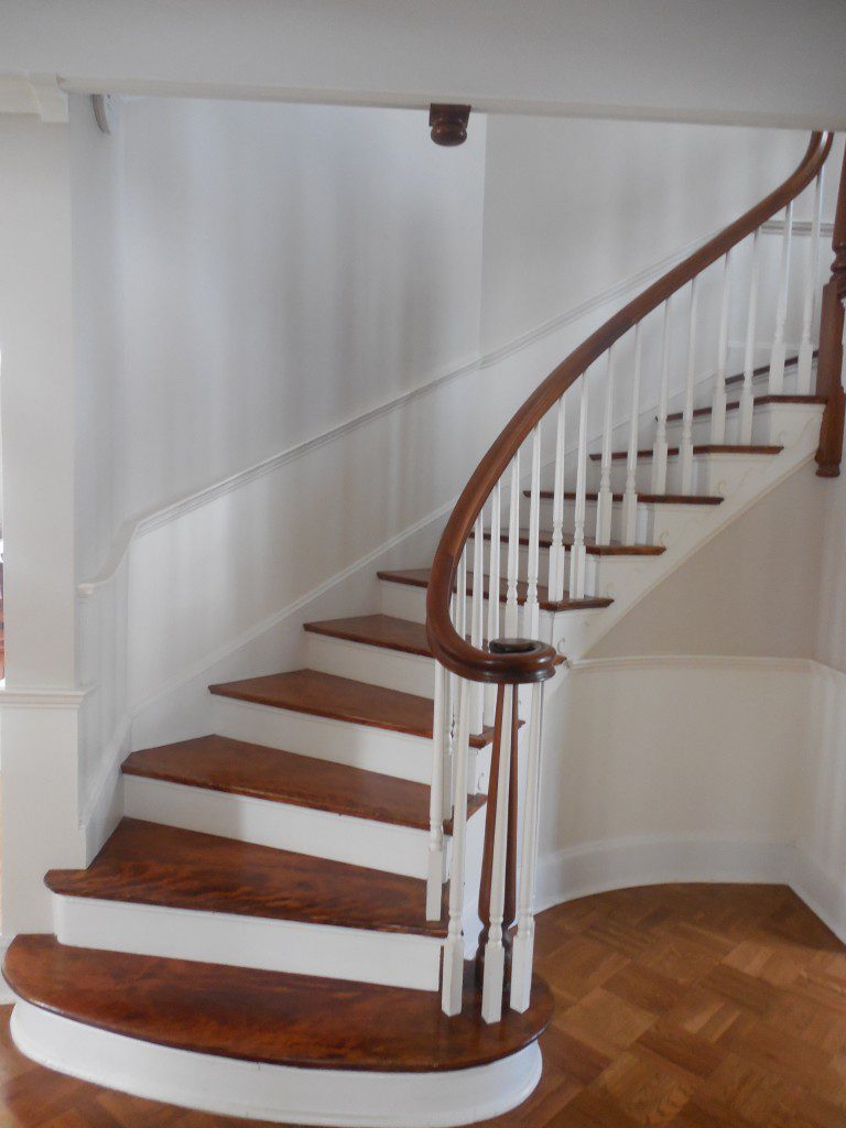 A staircase with wood treads and white railings.