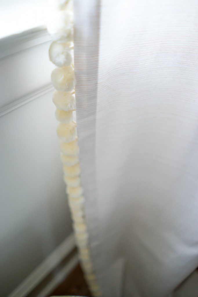 A white curtain with a string of beads hanging from it.