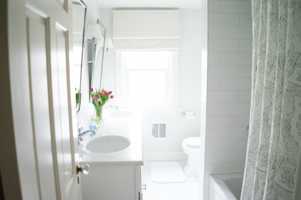 A bathroom with white tile and a sink.