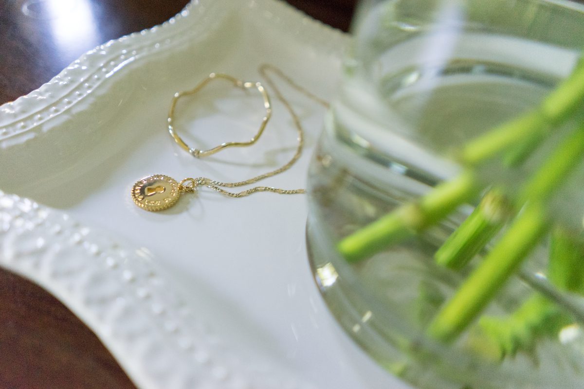 A gold necklace sitting on top of a white plate.