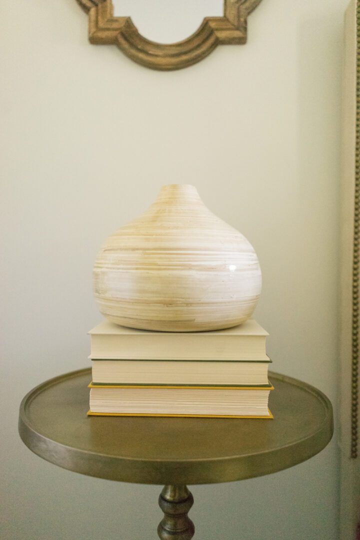 A vase sitting on top of books on a table.