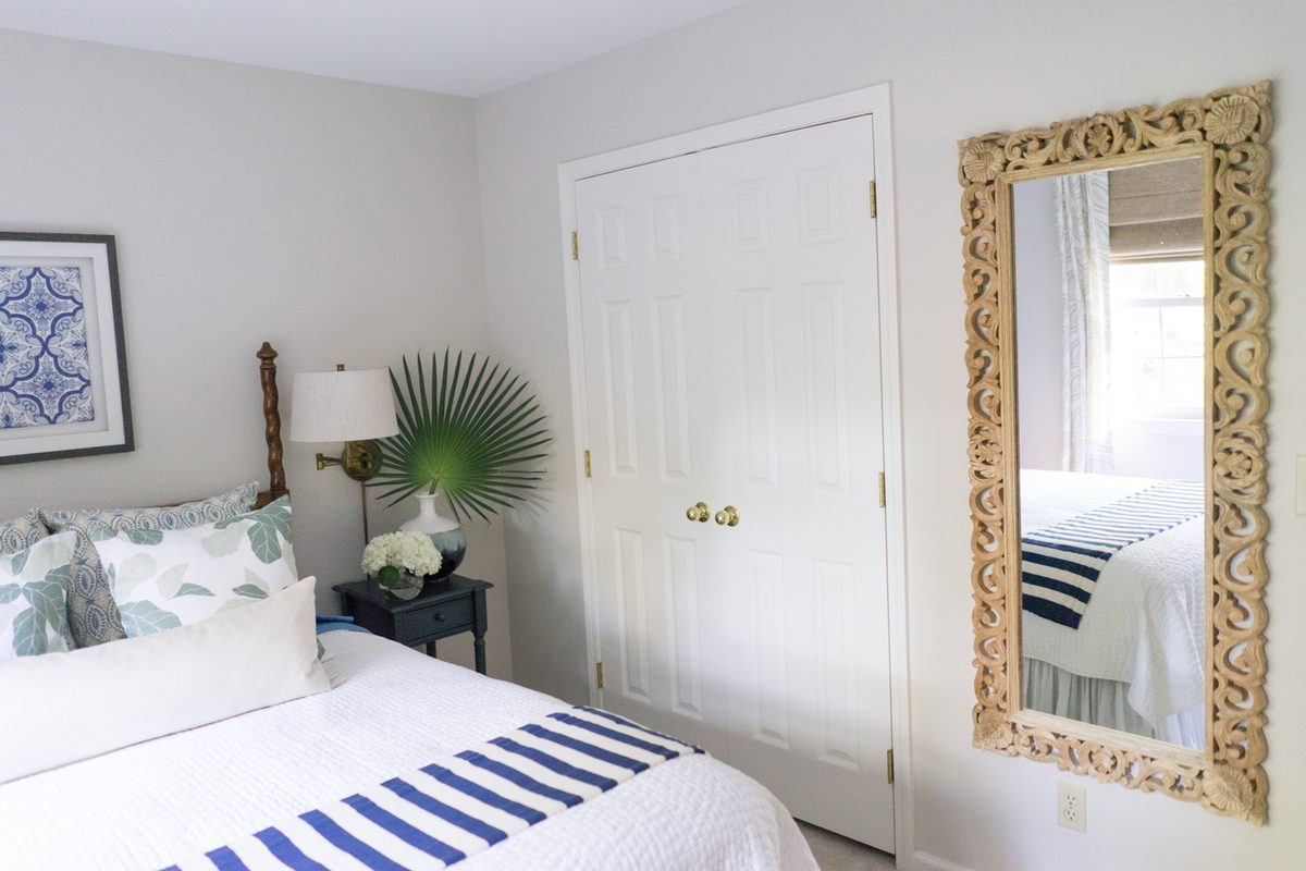 A bedroom with white walls and blue striped bedding.