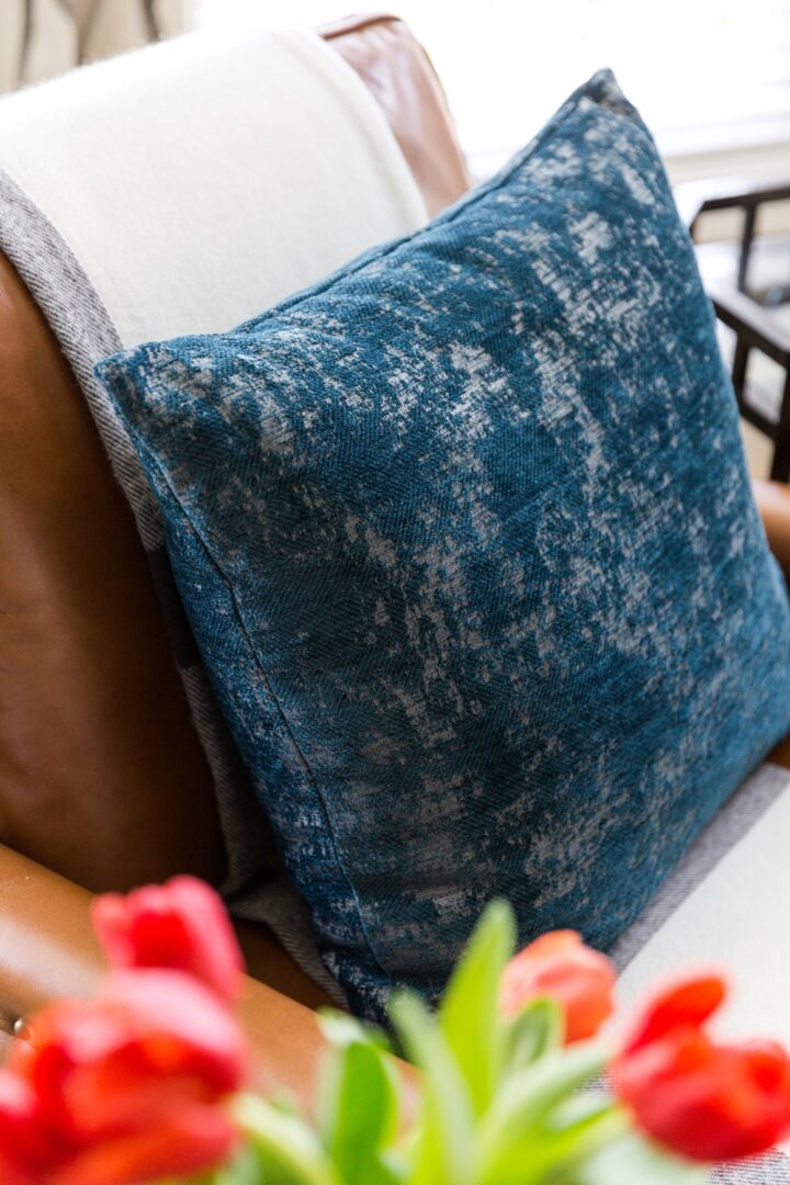 A blue pillow sitting on top of a wooden chair.