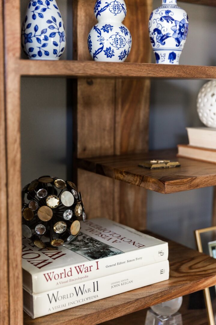 A book shelf with books and vases on it
