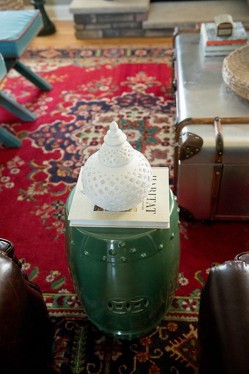A green stool with a white vase on top of it.