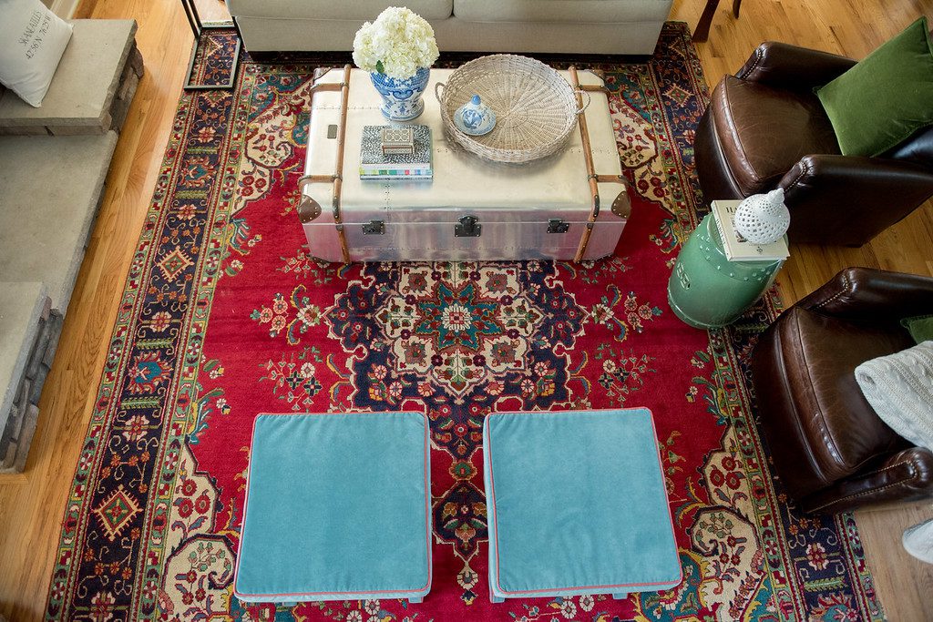 A red oriental rug with blue pillows on top of it.