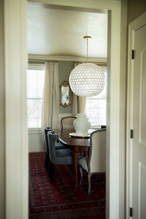A dining room with a table and chairs, a lamp and a mirror.