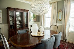 A dining room table with white vases and a chandelier.