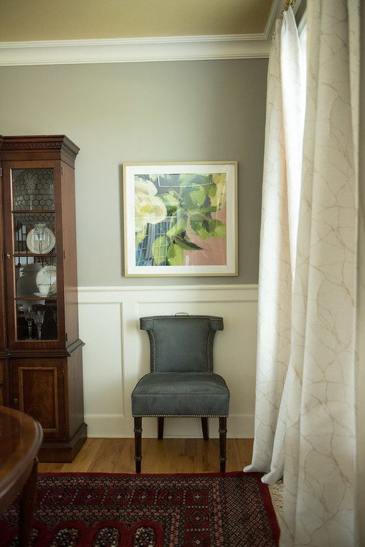 A chair in front of a painting on the wall.