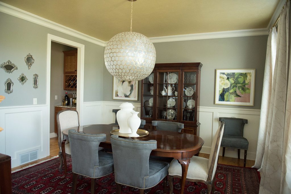 A dining room with a table and chairs, a china cabinet and a chandelier.