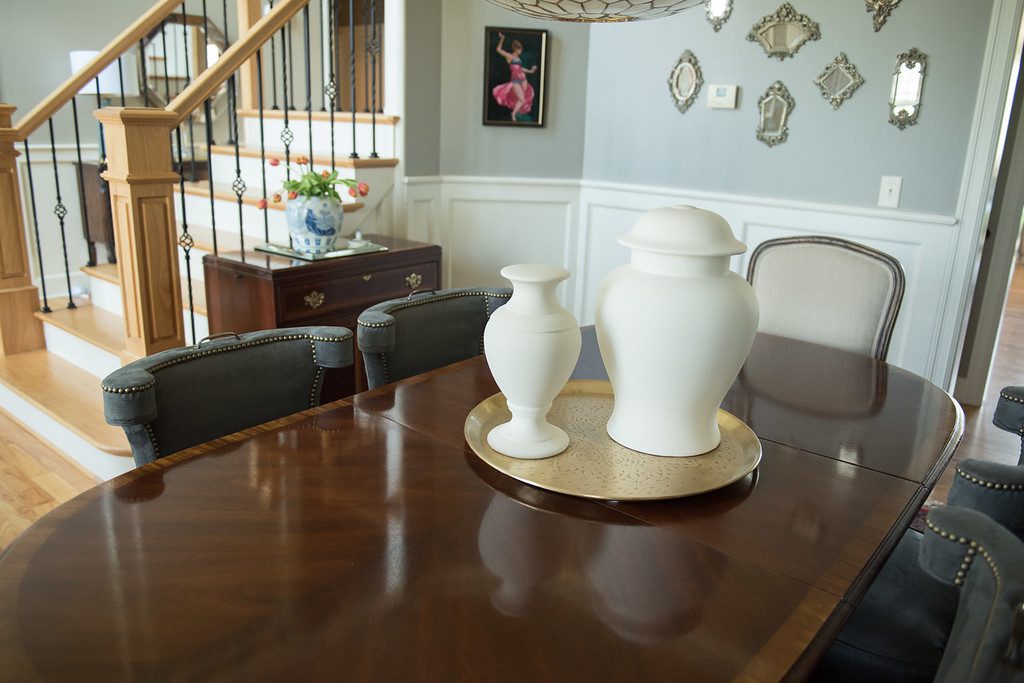 A dining room table with two vases on it.