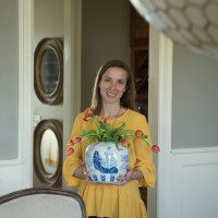 A woman holding a vase with flowers in it.