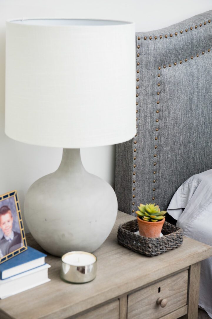 A lamp on the side of a bed next to a picture.