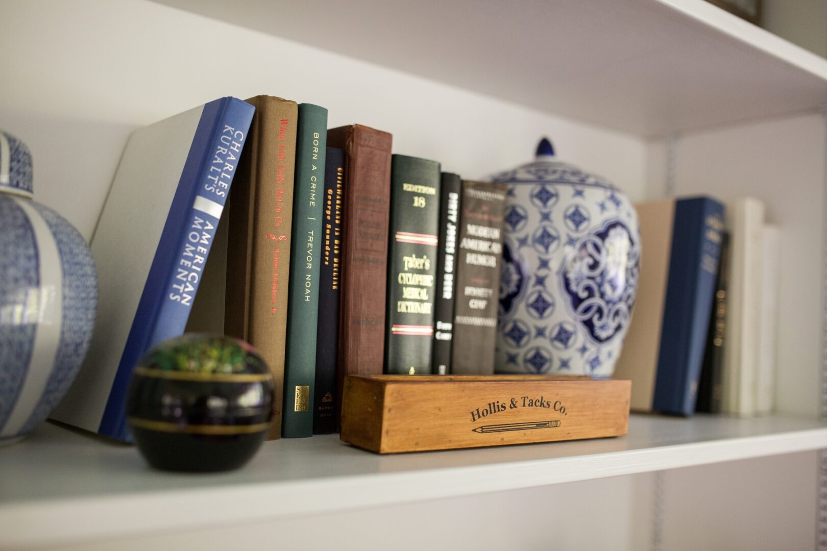 A bookshelf with books and a vase on top of it.